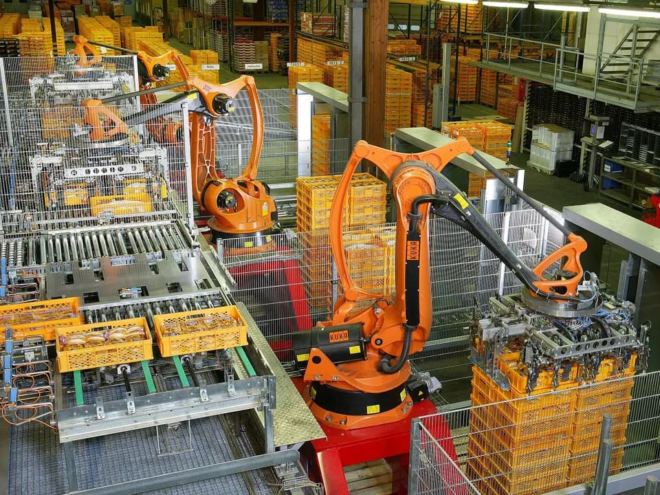 Промышленные роботы KUKA укладывают ящики с хлебом на поддоны в цехе пекарни