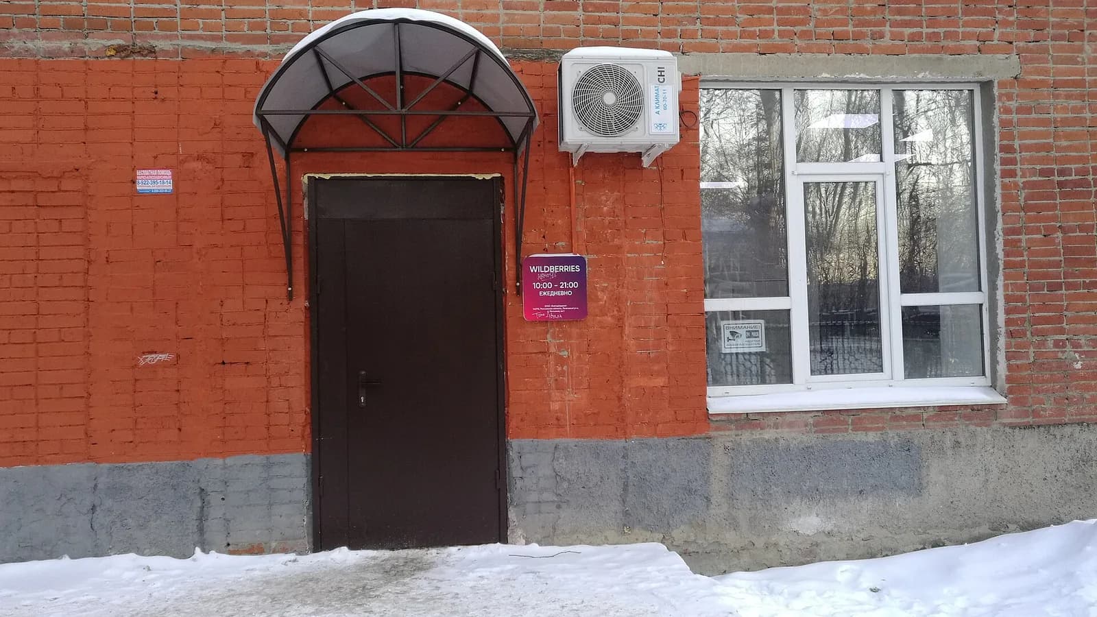 Вход в пункт выдачи Wildberries в кирпичном здании, над дверью козырёк, рядом табличка с логотипом