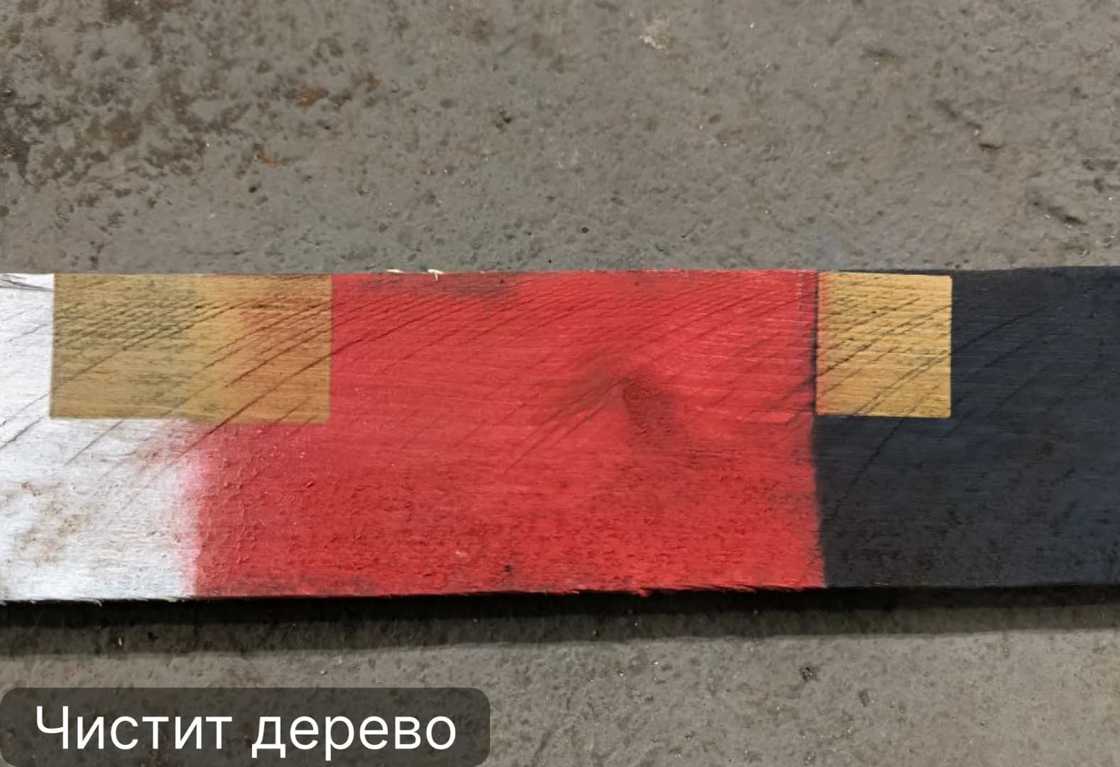 Аппарат PA 200 снимает красную и чёрную краску с деревянной доски, очищенные участки показывают чистую древесину